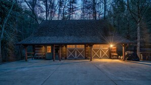 Un bâtiment d’un seul étage, doté d’un toit en pente, d’un garage avec des portes à croisillons et d’un espace extérieur aménagé avec des sièges.