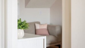 A modern living room with a white sofa, a small table, and a decorative plant.