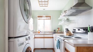 A compact kitchen with a washing machine, a stove, and a sink.
