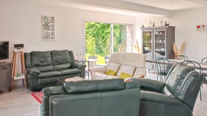 A living room with a green leather sofa, a white armchair, and a dining area with a table and chairs. - Homerez - House in Fort-Moville (Fort-Moville)