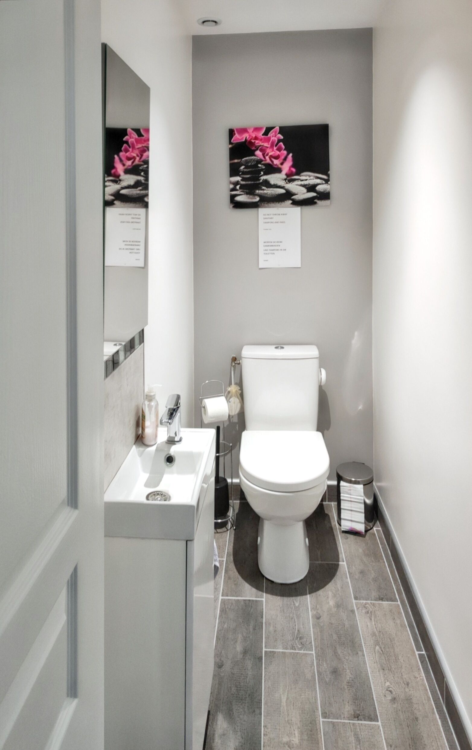 A modern bathroom with a toilet, sink, and mirror.