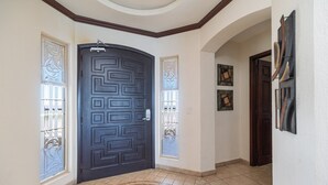 Un pasillo con una puerta oscura, paneles de vidrio decorativos y un piso estampado.