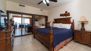 Un dormitorio con una cama grande, un aparador de madera, una mesita de noche y un ventilador de techo.