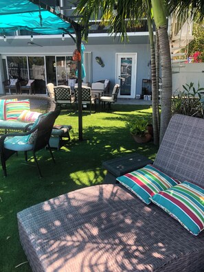 A patio area with wicker furniture, a green lawn, and a building with a sliding glass door.