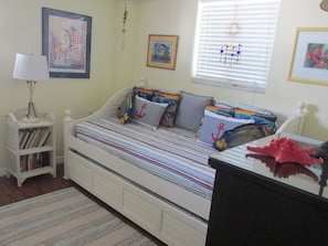A bedroom with a bed, a bookshelf, and a window with blinds.