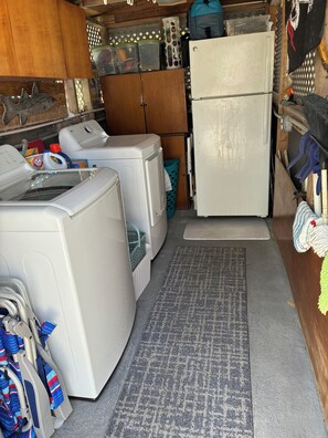 Eine kleine Küche mit Kühlschrank, Waschmaschine und Wäscheständer.