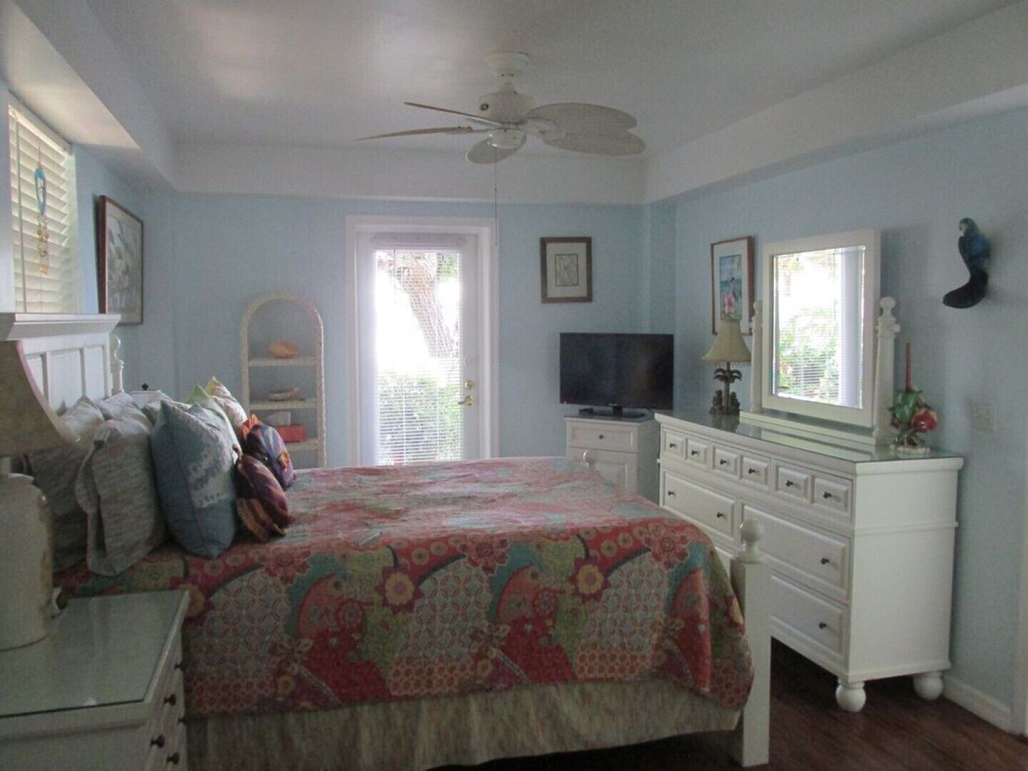 A bedroom with a bed, dresser, television, and a ceiling fan.