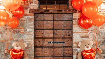 Um quarto rústico com porta de madeira, dois vasos em formato de urso com fitas vermelhas e uma parede de tijolos.