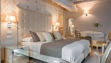 A modern bedroom with a tufted headboard, a glass bedside table, a desk with a chair, and a mirror.