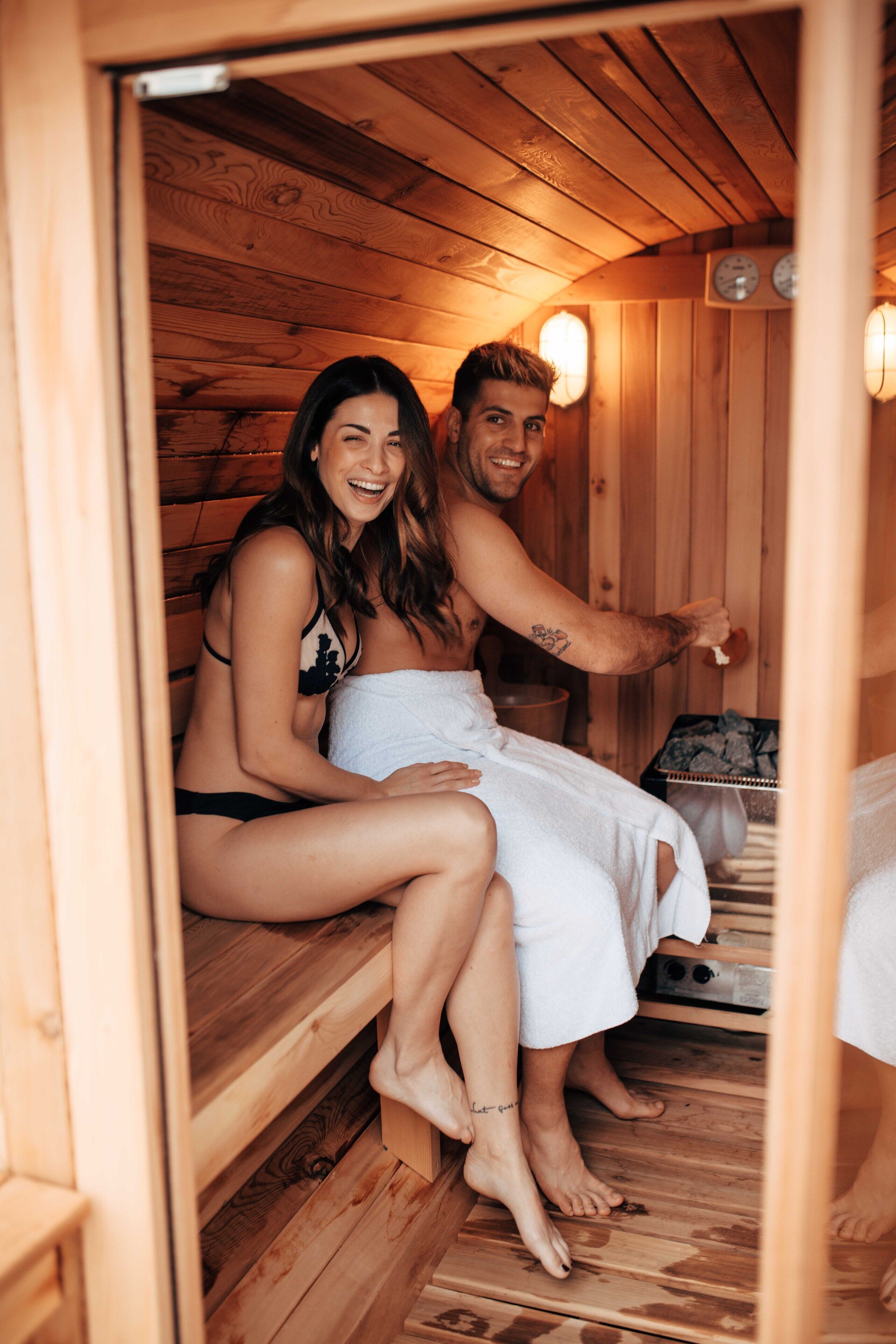 A wooden sauna with benches, a towel, and a clock on the wall.