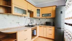 Eine Küche mit Holzausstattung, einem Edelstahlkühlschrank, einer Mikrowelle und einem Gasherd.