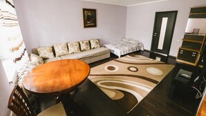 Ein Wohnzimmer mit einer Couch, einem kleinen Bett, einem Holztisch und einem gemusterten Teppich.