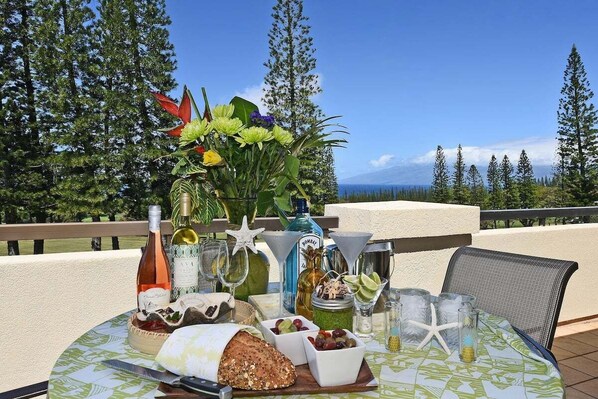 A table set with food and drinks on a balcony with a scenic view.