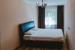 Cozy retreat with a single bed, chandelier, and window with curtains.