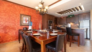 A dining area with a wooden table set for four, surrounded by dark leather chairs.