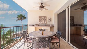 A balcony with a table and chairs, a ceiling fan, and a view of the ocean.