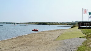 A beach with a sandy shore, a grassy area, and a body of water with boats. - 2 bedroom accommodation in Mount Hawke, near Redruth (Mount Hawke, near Redruth)