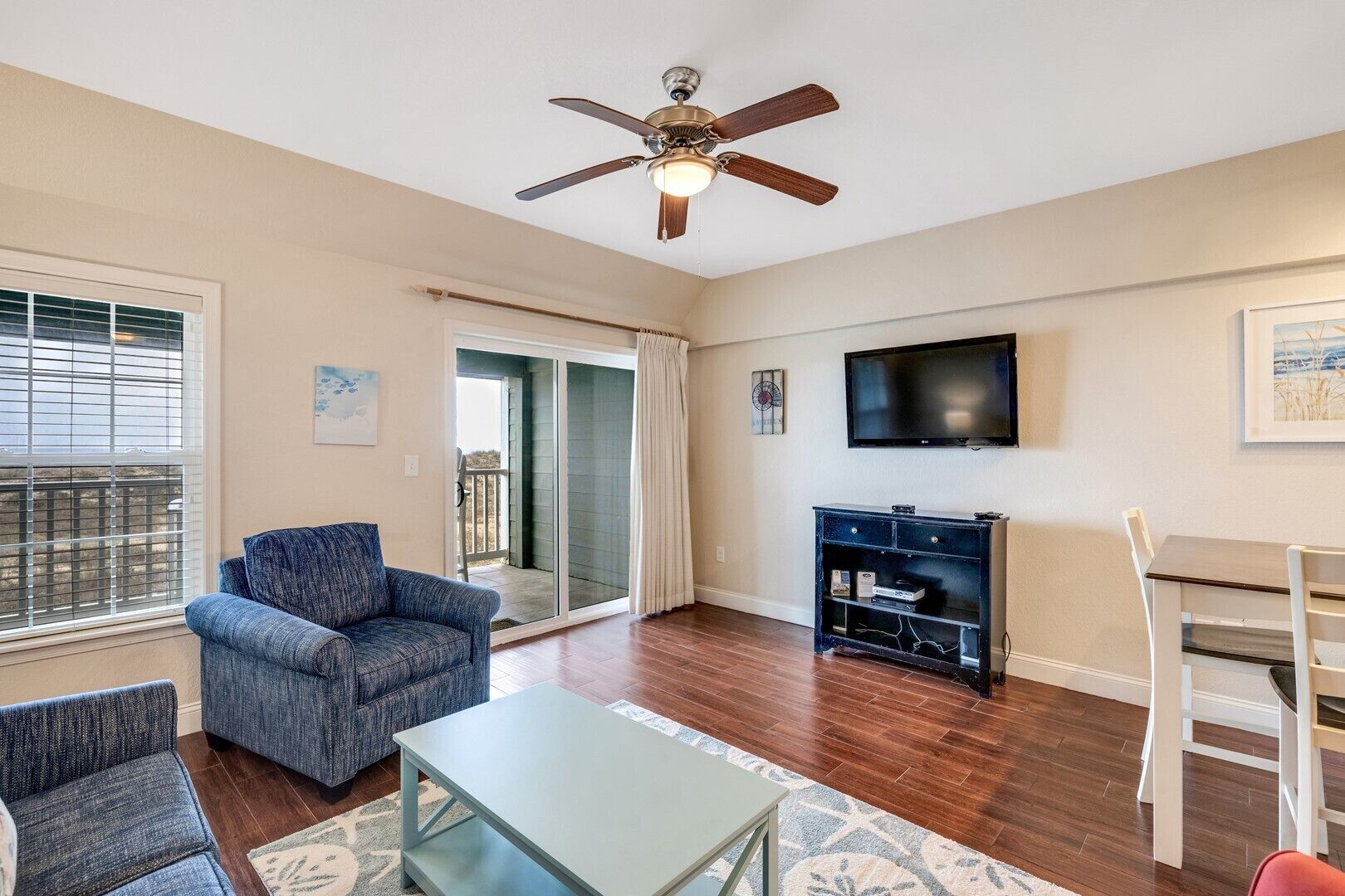 A living room with a ceiling fan, a TV, a fireplace, and a dining area with a table and chairs.