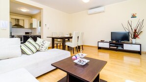 Ein modernes Wohnzimmer mit Sofa, Couchtisch, Fernseher und Essbereich.