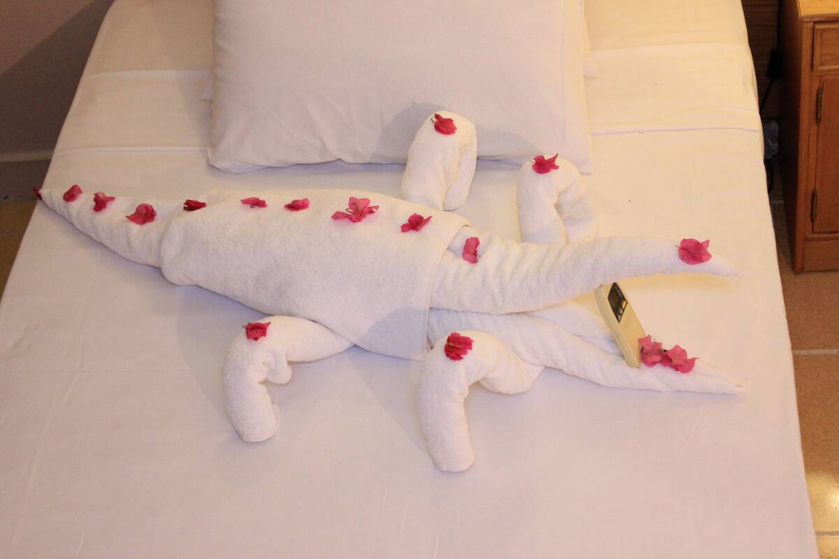 Ein Bett mit einer Handtuchskulptur eines Meereskreatur, möglicherweise eines Wals, verziert mit roten Blumen.
