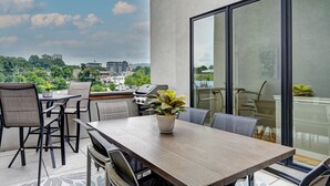 Un patio al aire libre con una mesa, sillas, una parrilla y una planta en maceta.