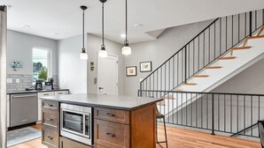 Una cocina moderna con una isla central, electrodomésticos de acero inoxidable e iluminación colgante.
