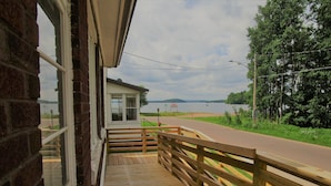 A wooden deck with a railing overlooking a lake and a road. - Close to Hurley, Trail access, near The Gile Flowage with Central Air & King Bed (Montreal)