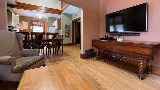 A living room with a wooden dining table, a sofa, and a TV on a wooden stand. - Close to Hurley, Trail access, near The Gile Flowage with Central Air & King Bed (Montreal)