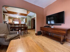 A living room with a wooden dining table, a sofa, and a TV on a wooden stand. - Close to Hurley, Trail access, near The Gile Flowage with Central Air & King Bed (Montreal)