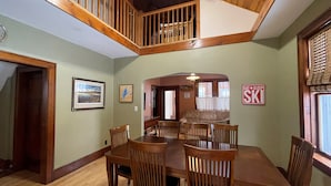 A dining area with a wooden table and chairs, a staircase, and a sign that says "EAT SLEEP SKI". - Close to Hurley, Trail access, near The Gile Flowage with Central Air & King Bed (Montreal)