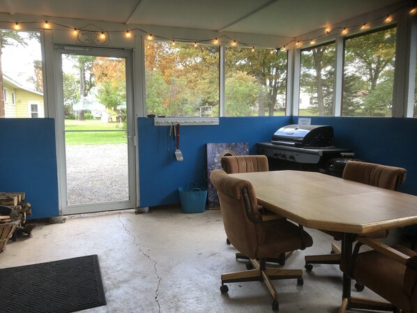 A covered outdoor area with a table and chairs, a grill, and a view of the outdoors. - Close to Hurley, Trail access, near The Gile Flowage with Central Air & King Bed (Montreal)