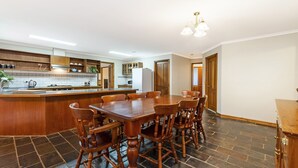 A spacious kitchen with a central island, wooden dining table, and chairs. - Ideal family holiday home in the seaside town of Warrnambool (WARRNAMBOOL)