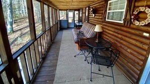 Een overdekte veranda met een bank, stoelen en een tafel.