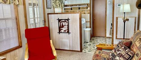 Uma sala de estar acolhedora com uma poltrona vermelha, um sofá estampado e teto de madeira.