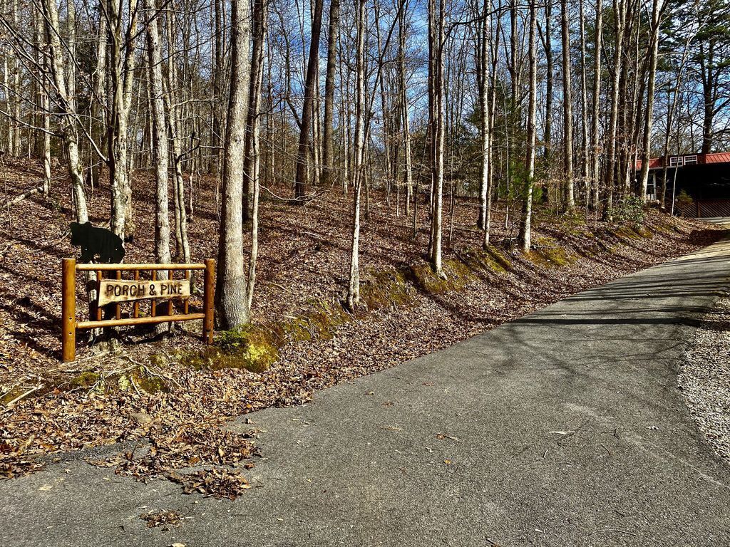 A sign labeled "PORCH & PINE" in a wooded area with a paved path.