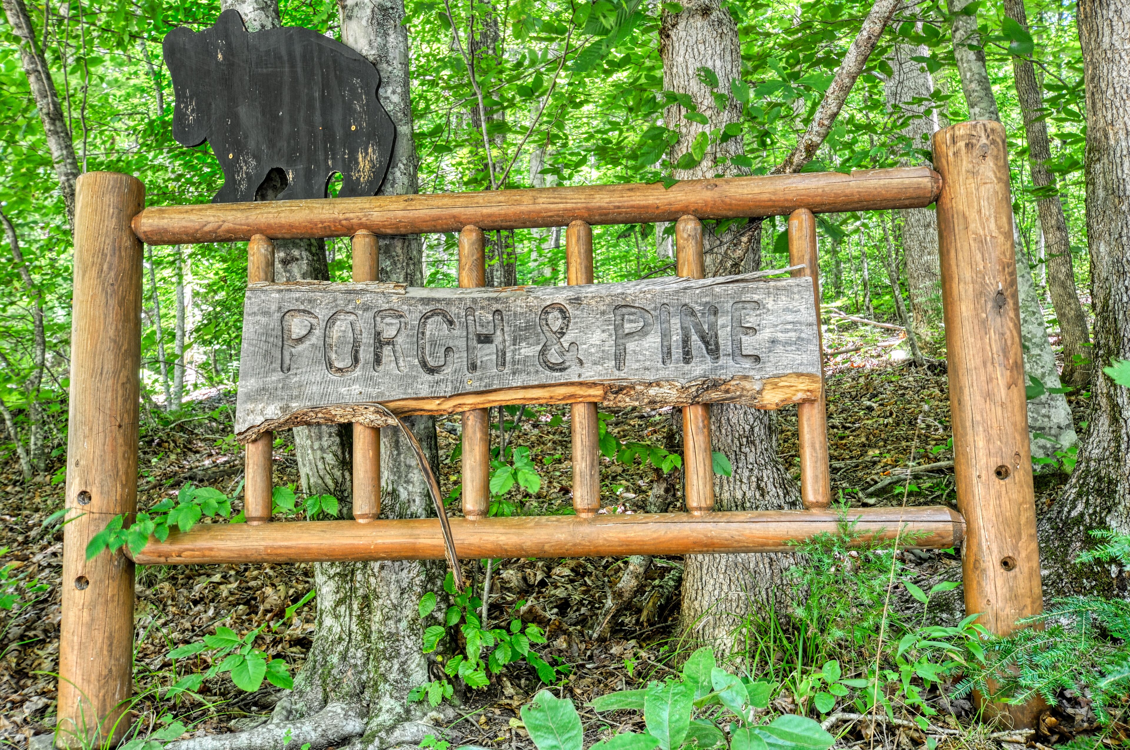 A wooden sign with the text 'PORCH & PINE' in a forest setting.