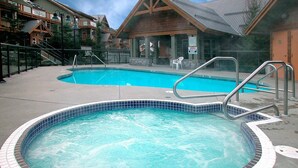 A hot tub with a tiled edge, surrounded by a concrete deck. - 90 Glaciers Reach, this 2br home has a hot tub & pool in Whistler Village (Whistler)