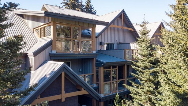 A multi-story lodge with a prominent balcony and large windows, surrounded by trees. - 90 Glaciers Reach, this 2br home has a hot tub & pool in Whistler Village (Whistler)