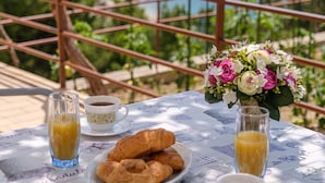 A table with croissants, coffee, and juice, overlooking a scenic view of the sea and mountains. - Rooms Sani - Double Room with Terrace and Sea View (S1) (Brela)