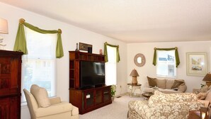 A living room with a television, two sofas, a cabinet, and a small side table.