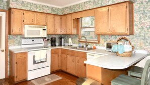 A kitchen with wooden cabinets, a microwave, a stove, a sink, and a toaster.