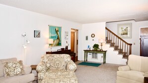 A living room with a sofa, armchair, and a coffee table. There is a staircase leading to another room.
