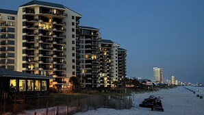 A beachfront hotel with multiple balconies, a sandy beach in the foreground, and a clear sky. - Beach Front Condo with Endless Gulf Views!   (Panama City Beach)