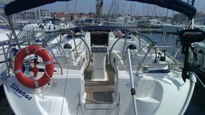 A boat with a white deck, a steering wheel, and a life preserver.