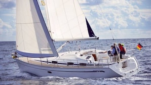 A sailboat with a cabin and deck seating, sailing on the water.