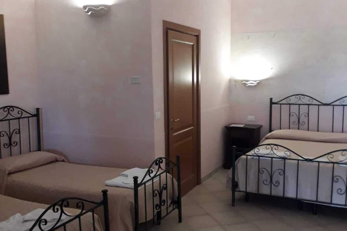 Ein Zimmer mit zwei Betten, einer Tür und einem Nachttisch.