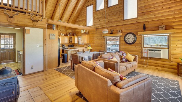 Ein gemütliches Blockhaus-Interieur mit Essbereich, Küche und Wohnzimmer mit Ledersofas.