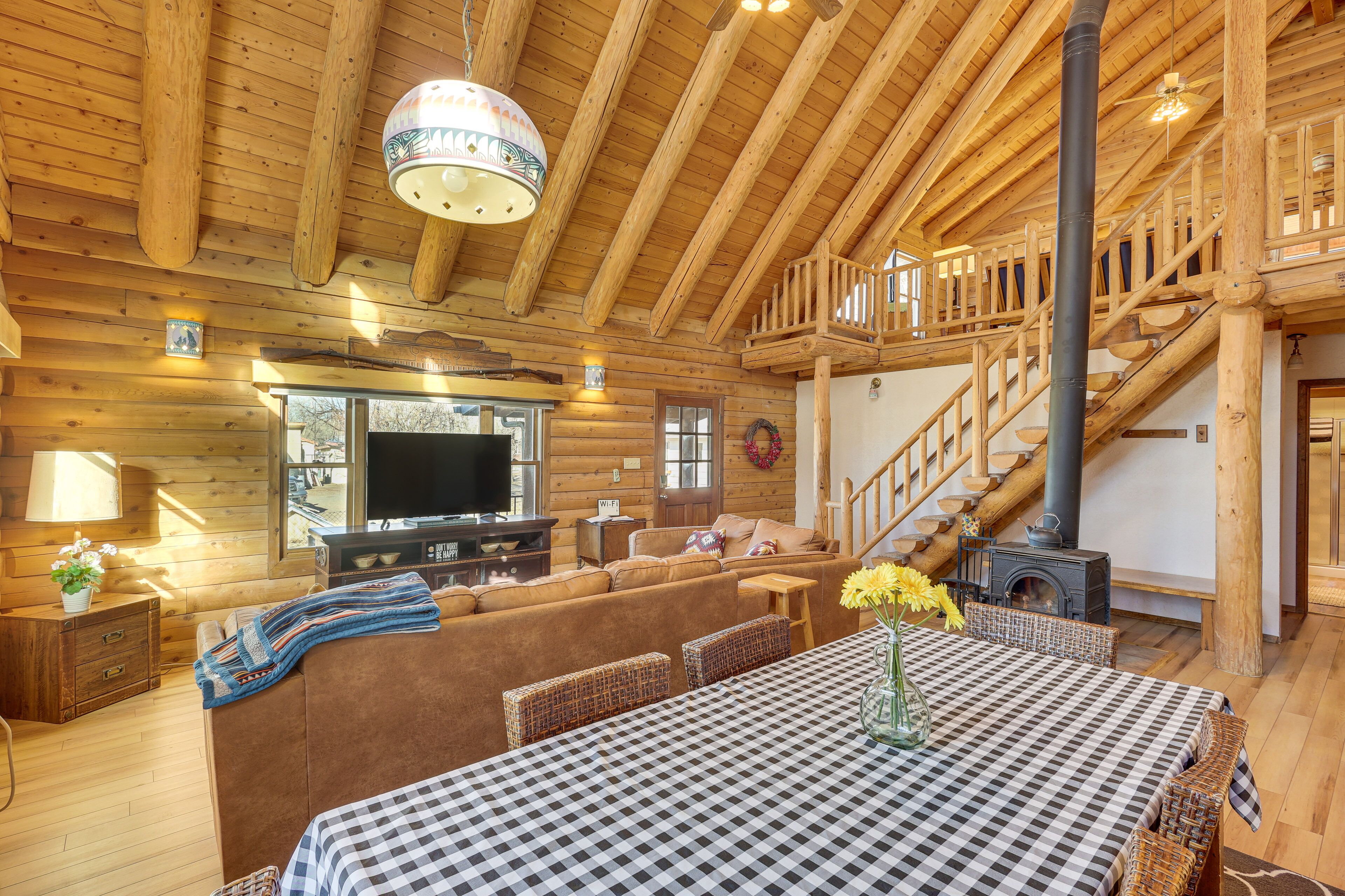 A log cabin interior with a checkered table, sofa, and a fireplace.