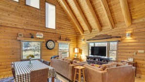 Ein gemütliches Holzblockhaus-Interieur mit Essbereich, Sofa und Fernseher.