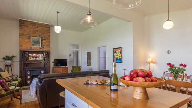A spacious living room with a wooden coffee table, a fireplace, and a television. - Lucy's Cottage in beautiful Kyneton (Kyneton)
